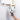 A man holds a handheld electronic meter device with a black cable toward a wall-mounted gas meter and brass pipe fittings in a home setting.